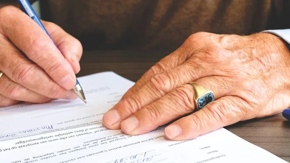 A person signing a printed document with a pen